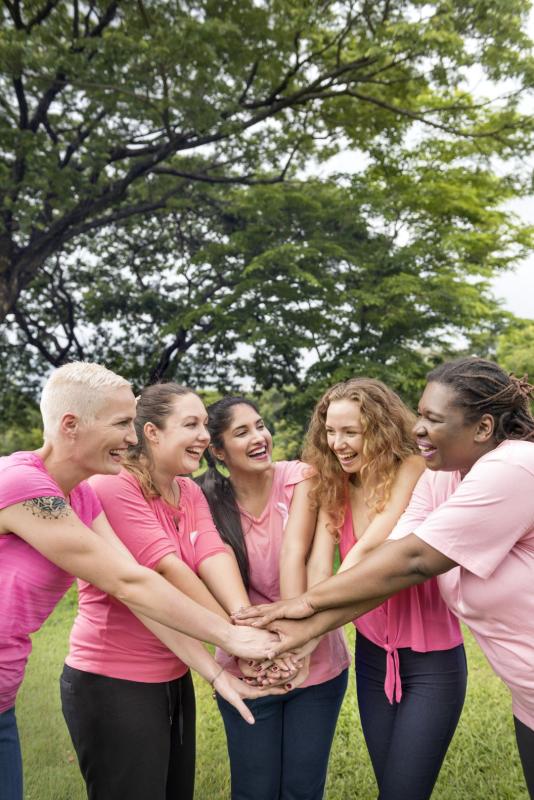 Femmes heureuses avec mains jointes en t-shirts roses /Gelukkige vrouwen met gevouwen handen in roze t-shirts