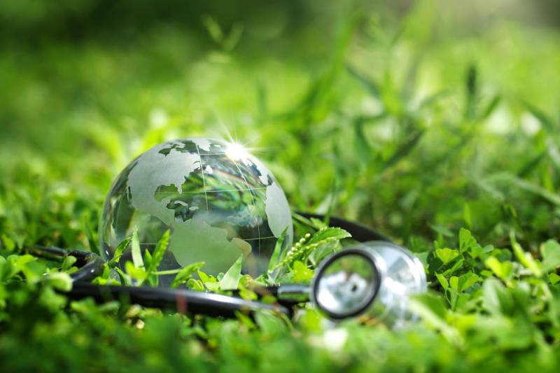 Globe terrestre en verre posé sur de l’herbe, accompagné d’un stéthoscope, symbolisant le lien entre santé humaine et environnement Globe terrestre en verre posé sur de l’herbe, accompagné d’un stéthoscope, symbolisant le lien entre santé humaine et environnement