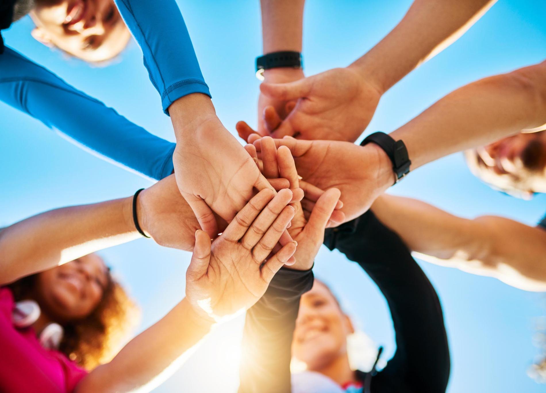 Group of joined hands with a beautiful sun