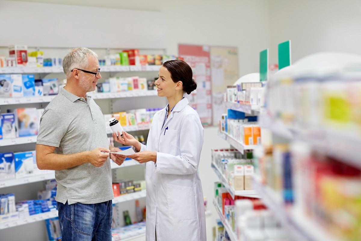 pharmacienne présentant un médicament à un homme âgé / apotheker presenteert medicijnen aan een oudere man