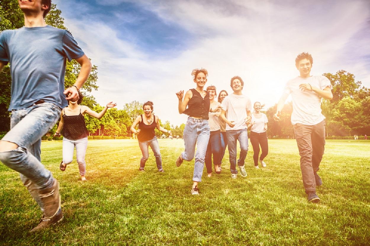 Groupe de jeunes amis courant ensemble dans un parc / Groep van jonge vrienden rent samen in een park